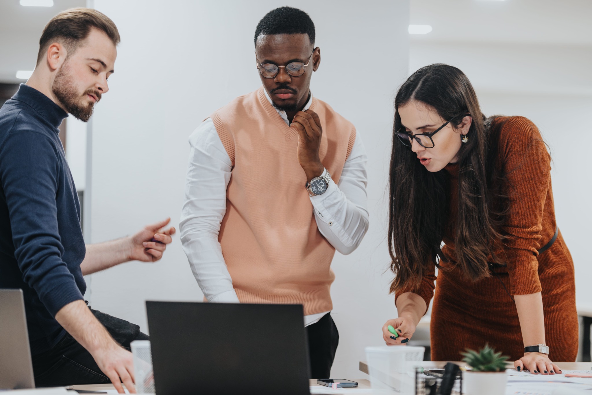 Three colleagues lean over a table during a working session.